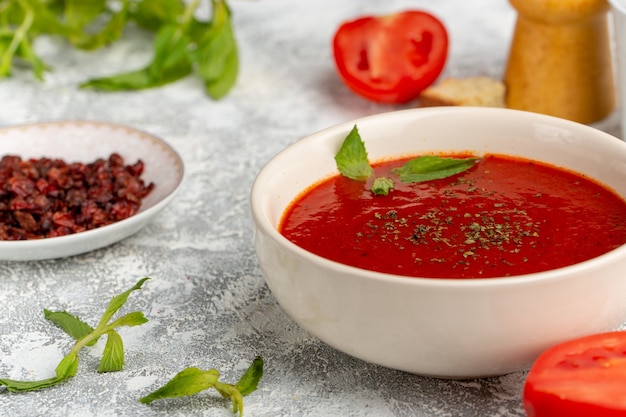 Foto grátis vista frontal de perto deliciosa sopa de tomate com verdes em cinza, refeição de sopa de vegetais jantar