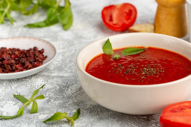 Vista frontal de perto deliciosa sopa de tomate com verdes em cinza, refeição de sopa de vegetais jantar