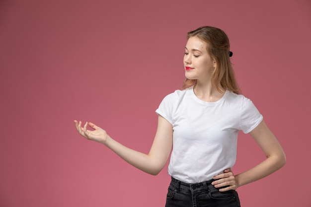 Vista frontal de perto jovem mulher atraente em camiseta branca posando com um sorriso na parede rosa modelo cor feminino jovem