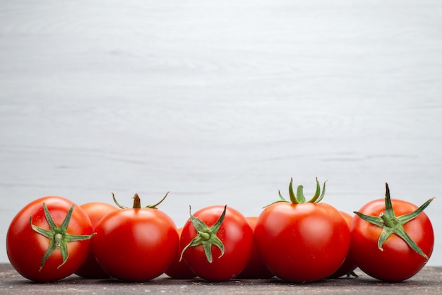 Vista frontal de perto tomates vermelhos frescos maduros no fundo branco vegetais frutas cor alimentos