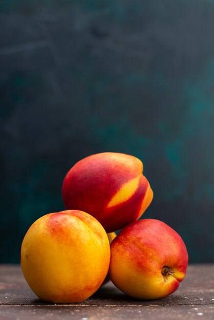 Vista frontal de pêssegos frescos, doces e suaves em frutas de parede escura, planta de árvore fresca e suave