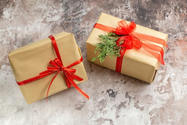 Vista frontal de presentes de Natal bonitos amarrados com laços vermelhos em uma mesa de luz