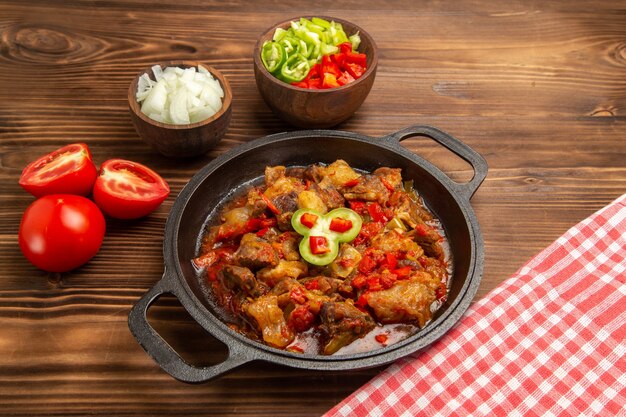 Vista frontal de refeição de vegetais cozidos com salada de pimentão fatiado em superfície marrom