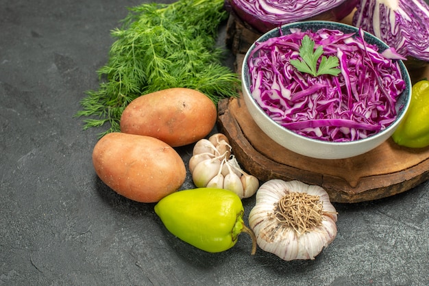 Vista frontal de repolho roxo com verduras e legumes na mesa escura salada dieta saudável saúde