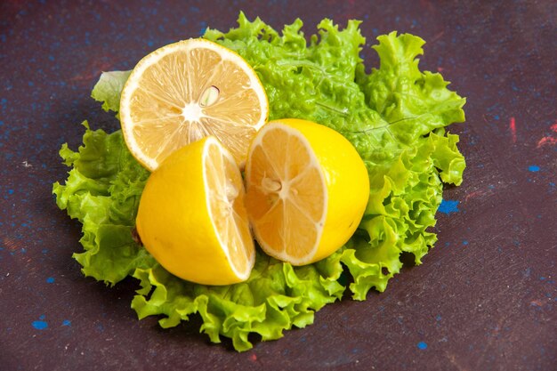 Vista frontal de rodelas frescas de limão com salada verde no espaço escuro