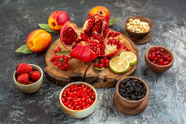 Vista frontal de romãs fatiadas com pêssegos em uma árvore frutífera de mesa clara-escura