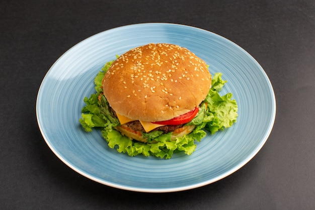 Vista frontal de sanduíche de frango com salada verde e vegetais dentro do prato na mesa escura