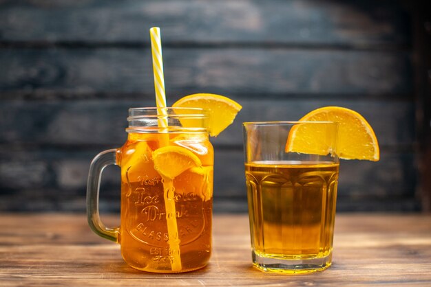 Vista frontal de suco de laranja fresco dentro da lata com canudo escuro.