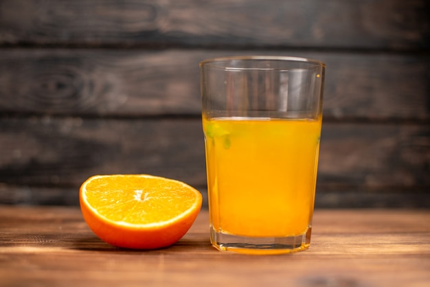 Vista frontal de suco de laranja fresco em um copo servido com hortelã e limão em uma mesa de madeira
