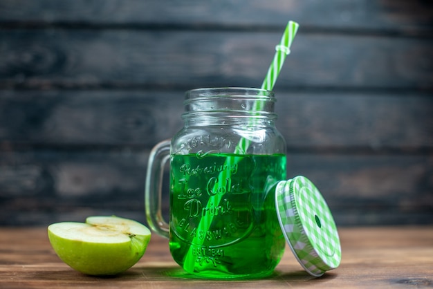 Vista frontal de suco de maçã verde dentro da lata com maçãs frescas na mesa escura.