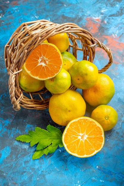 Vista frontal de tangerinas frescas na cesta de vime na superfície azul