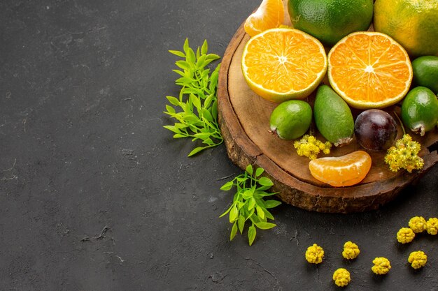 Vista frontal de tangerinas verdes frescas com feijoas e doces no espaço escuro