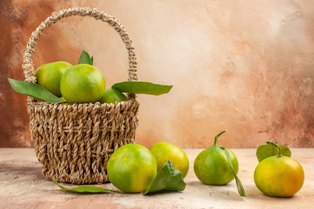 Vista frontal de tangerinas verdes frescas dentro da cesta com fundo claro suco foto cor fruta suave