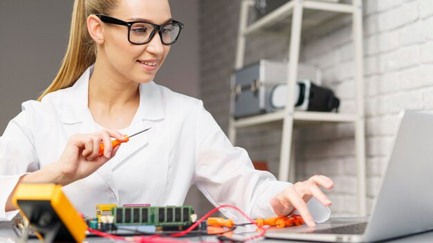 Vista frontal de técnica feminina com eletrônica e laptop