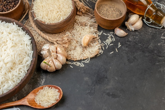 Vista frontal de tigelas marrons de arroz longo perfeitas na toalha de cor nua garrafa de óleo caída pimentas na mesa escura