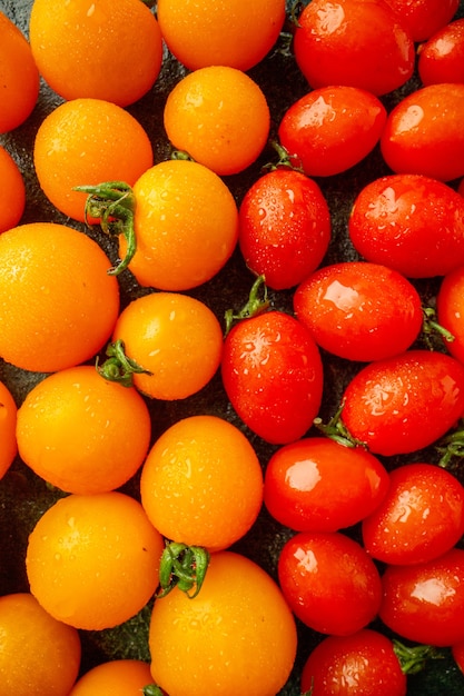 Vista frontal de tomates laranja com tomates em uma superfície verde escura