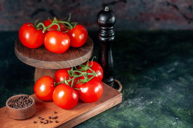 Vista frontal de tomates vermelhos frescos com pimenta em fundo escuro