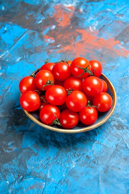 Vista frontal de tomates vermelhos frescos dentro do prato na mesa azul