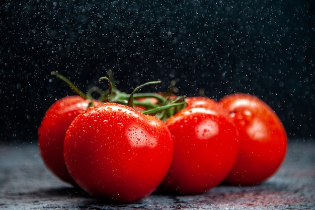 vista frontal de tomates vermelhos frescos em fundo escuro