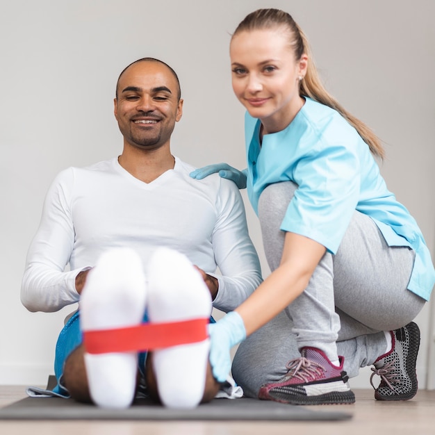 Vista frontal de um fisioterapeuta masculino e feminino fazendo exercícios