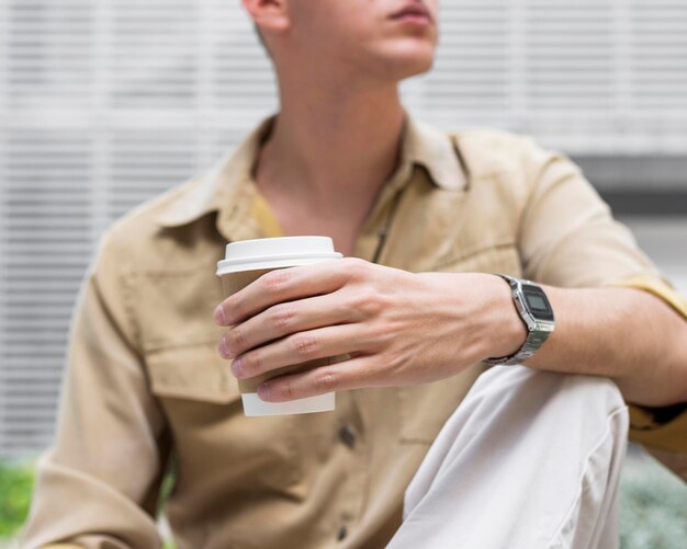 Vista frontal de um homem ao ar livre segurando uma xícara de café