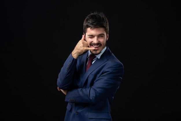 Vista frontal de um homem barbudo emocional fazendo gesto de óculos na parede escura isolada