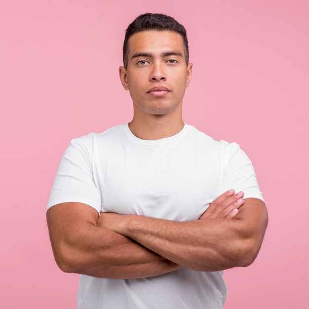 Vista frontal de um homem bonito posando com os braços cruzados