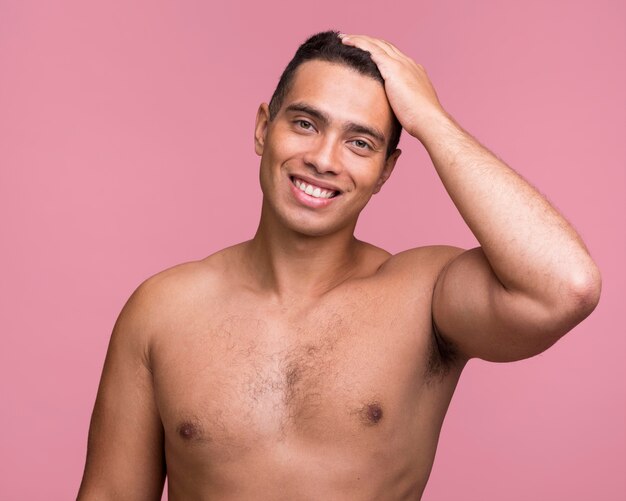 Vista frontal de um homem bonito sorridente posando sem camisa