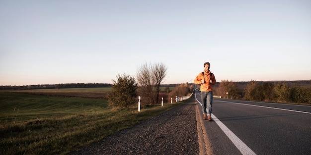 Vista frontal de um homem caminhando sozinho na estrada