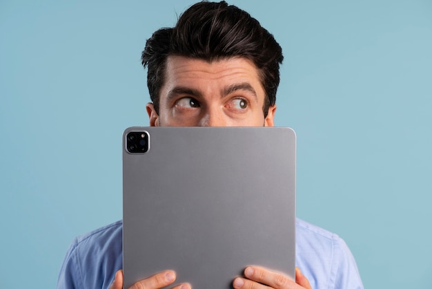 Vista frontal de um homem cobrindo o rosto com um tablet