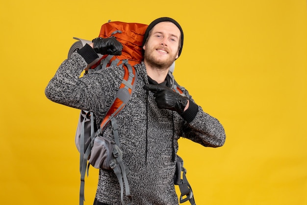 Foto grátis vista frontal de um homem confiante caroneiro com luvas de couro e mochila mostrando os músculos do braço