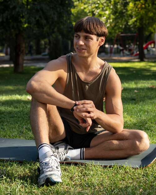 Vista frontal de um homem de camiseta regata malhando na natureza