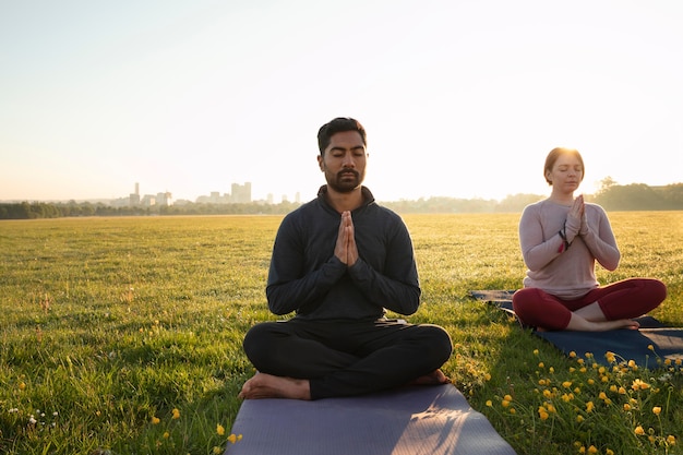 Foto grátis vista frontal de um homem e uma mulher meditando ao ar livre