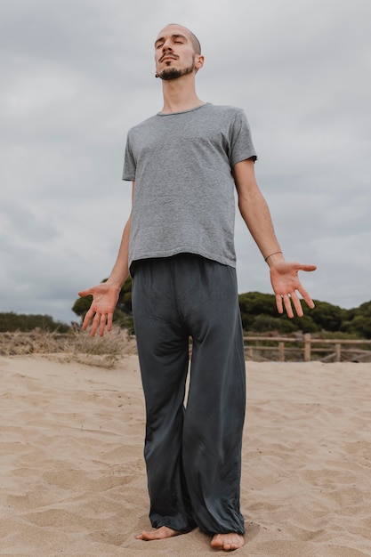 Vista frontal de um homem fazendo ioga ao ar livre