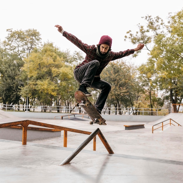 Vista frontal de um homem fazendo manobras com o skate ao ar livre