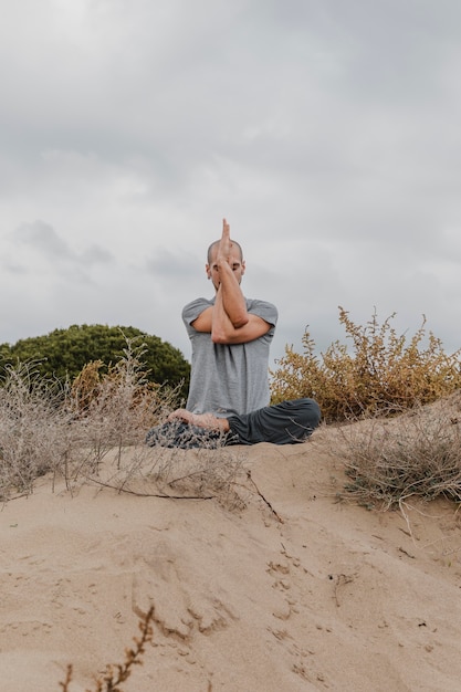 Vista frontal de um homem meditando do lado de fora enquanto pratica ioga