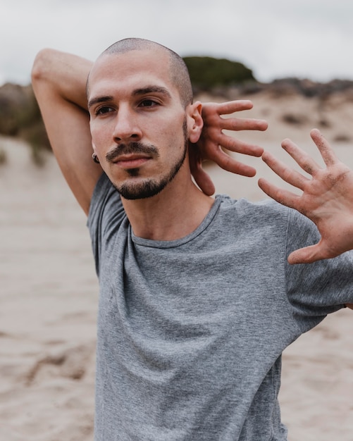 Vista frontal de um homem na praia fazendo ioga