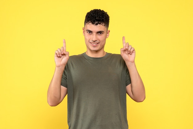 Vista frontal de um homem o cara sorridente levanta os dedos e olha para frente