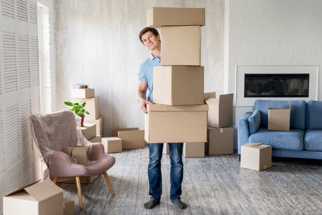 Vista frontal de um homem segurando várias caixas para se mudar