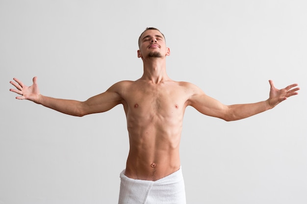 Vista frontal de um homem sem camisa posando em uma toalha