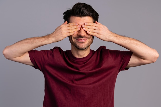 Vista frontal de um homem tímido cobrindo os olhos com as mãos