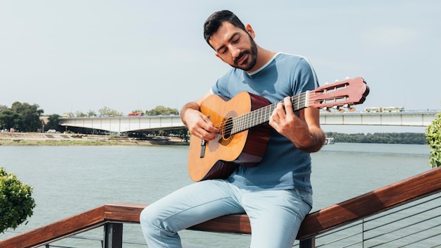 Vista frontal de um homem tocando violão