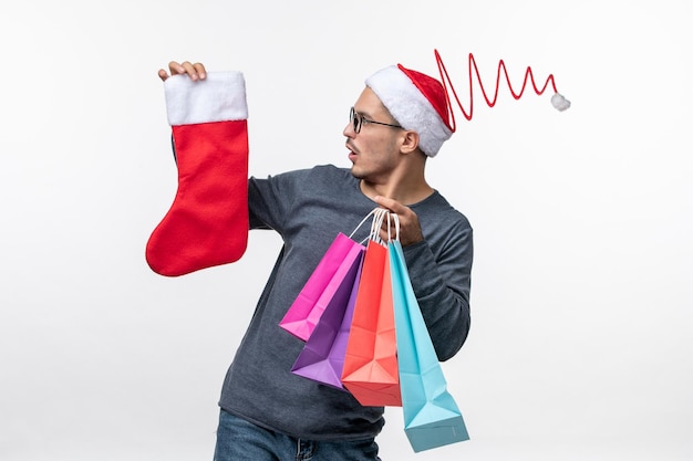 Vista frontal de um jovem após as compras de natal na parede branca