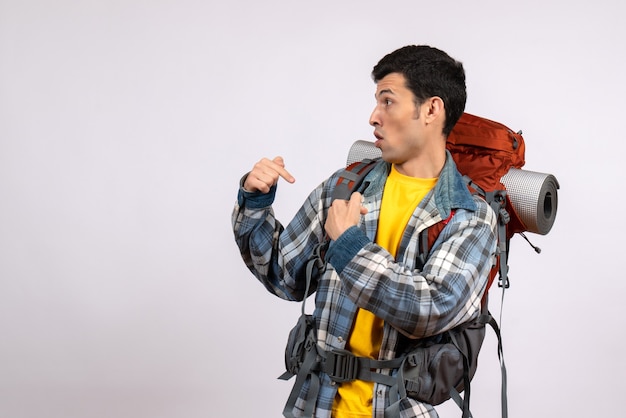 Vista frontal de um jovem com uma mochila apontando para si mesmo