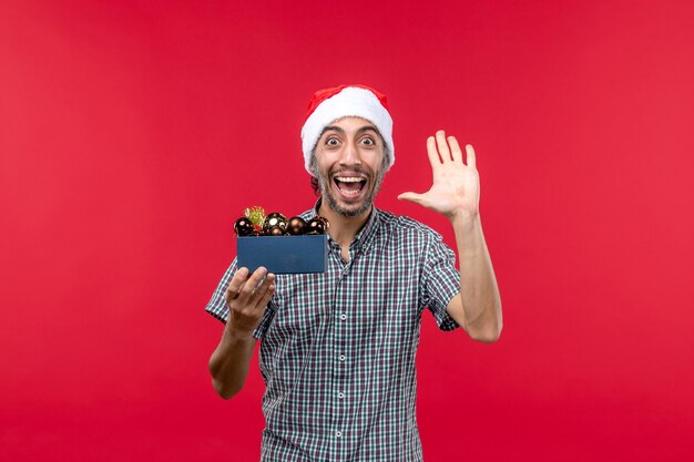 Vista frontal de um jovem homem com brinquedos de árvore de Natal em vermelho