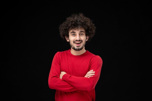 Vista frontal de um jovem homem de camisa vermelha na parede preta