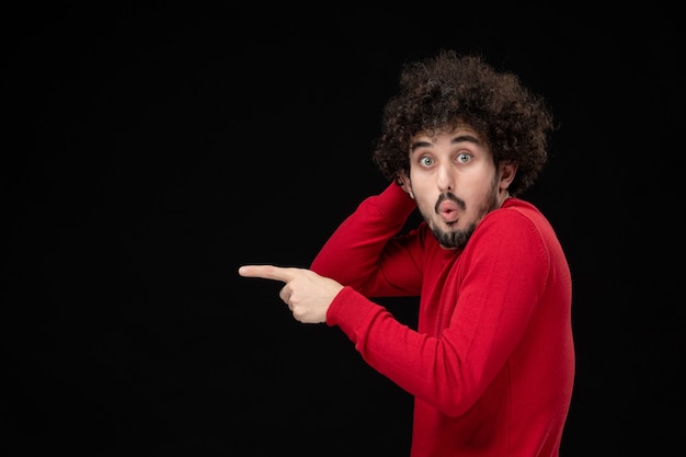 Vista frontal de um jovem homem de camisa vermelha na parede preta