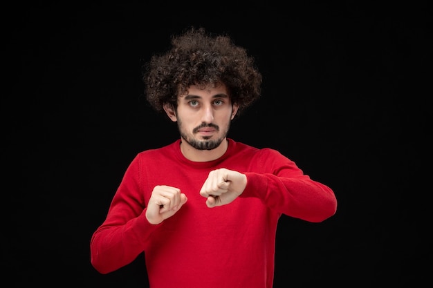 Vista frontal de um jovem homem de camisa vermelha na parede preta