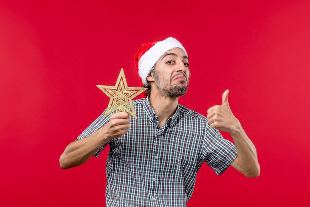 Foto grátis vista frontal de um jovem segurando o brinquedo estrela no vermelho