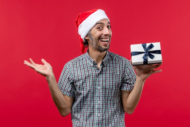 Vista frontal de um jovem segurando o presente de Natal no vermelho